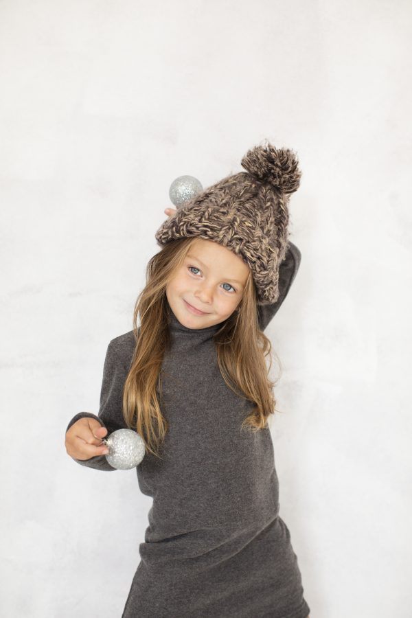 Jeune fille souriante portant un bonnet en laine recyclée et une robe col roulé grise de la collection enfant Etikashion.